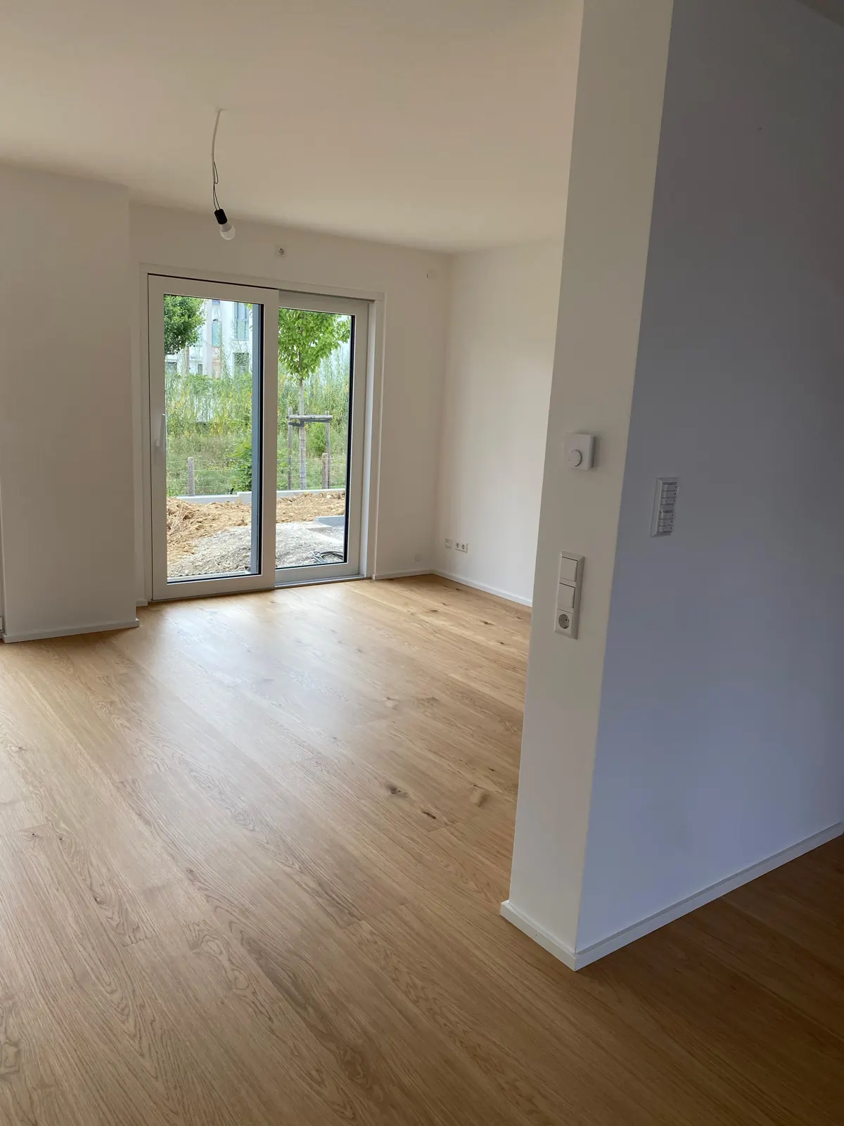 Gereinigter, leerer Wohnraum mit Holzboden und Terrassentür in einem Neubau nach der Bauendreinigung