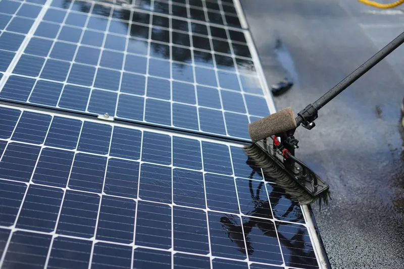Bürste an einer Teleskopstange reinigt nasse Solarmodule