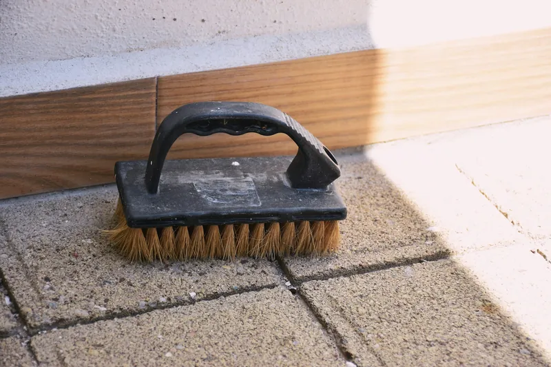 Schrubberbürste liegt auf hellen Pflastersteinen einer Terrasse